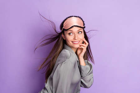 Photo portrait of girl in grey pajama sleeping mask smiling curious looking blank space isolated pastel purple color backgroundの写真素材