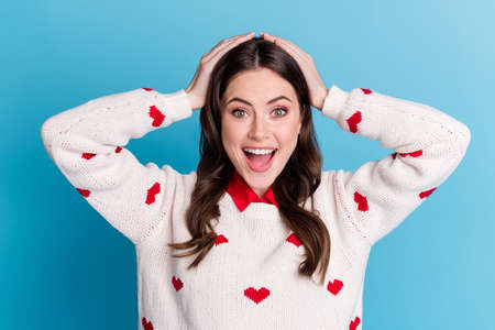 Photo of surprised funny young lady wear hearts print sweater open mouth arms head isolated blue...