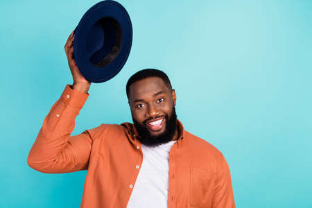 Photo of young african man happy positive smile gentleman hold headwear greeting isolated over teal color backgroundの写真素材