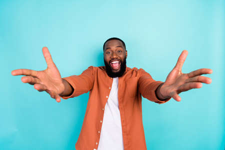 Photo of young excited black man happy positive smile open hands hug welcome isolated over turquoise...