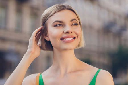 Photo of cheerful candid pretty blonde lady look away think enjoy spring wear green dress urban city outdoorsの写真素材