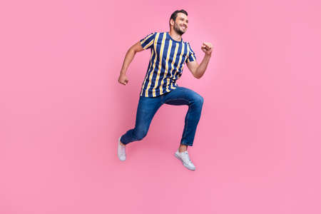 Full body profile photo of funny millennial brunet guy run wear t-shirt jeans sneakers isolated on pink backgroundの写真素材