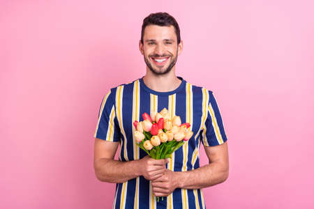 Photo portrait man keeping tulips bunch smiling isolated pastel pink color backgroundの写真素材