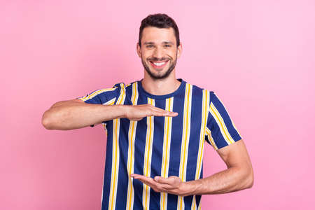Photo portrait man smiling showing size striped t-shirt isolated pastel pink color backgroundの写真素材