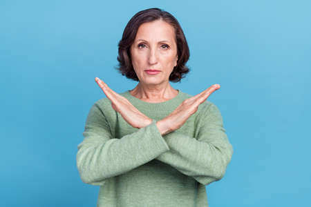 Photo of elder white hair lady show no sign expression wear green jumper isolated on blue color...