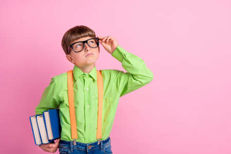 Photo of young school boy curious look empty space pupil book materials stylish green shirt isolated...
