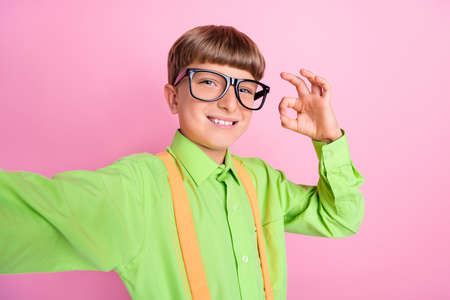 Photo of young school boy age record video show okay alright deal symbol choose ads isolated over...