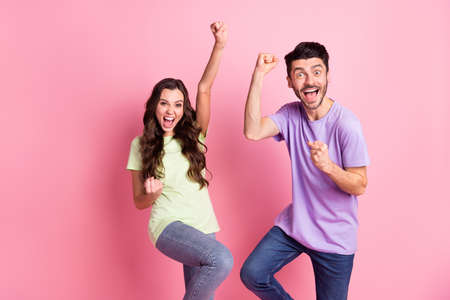 Portrait of attractive cheerful lucky couple rejoicing having fun isolated over pink pastel color...