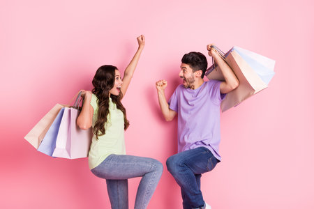 Portrait of attractive lucky trendy cheerful couple carrying news things clothes having fun black friday isolated on pink pastel color backgroundの写真素材
