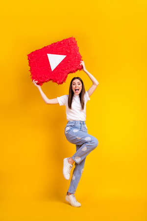 Full length photo of young excited woman hold paper pinata video play social media isolated over yellow color backgroundの写真素材