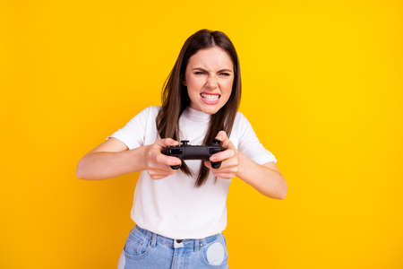 Photo of young girl unhappy play video game joystick angry competition isolated over yellow color backgroundの写真素材