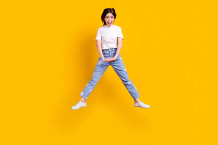 Full length photo of young girl happy positive smile have fun jump up isolated over yellow color...