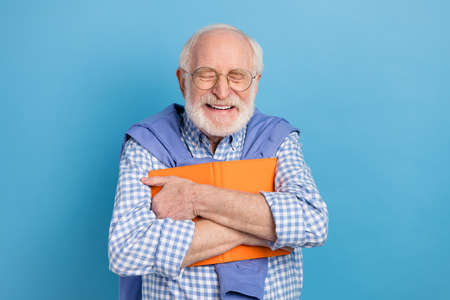 Photo of optimistic old grey hairdo man hold book wear spectacles blue shirt isolated on pastel...