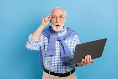 Photo of impressed old grey hairdo man hold laptop wear spectacles blue shirt isolated on pastel color backgroundの写真素材