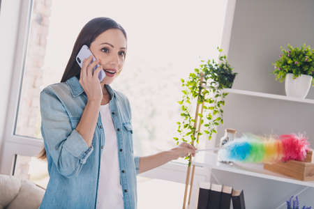 Photo of cute brunette millennial lady talk telephone clean brush wear jeans shirt from home alone