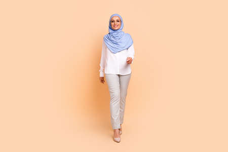 Full body photo of millennial arabic modern lady go wear headscarf shirt eyewear pants stilettos isolated on peach backgroundの写真素材
