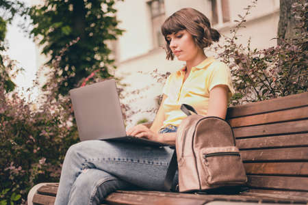 Photo of serious charming focused young woman hold hands computer sit bench outside outdoors city townの写真素材