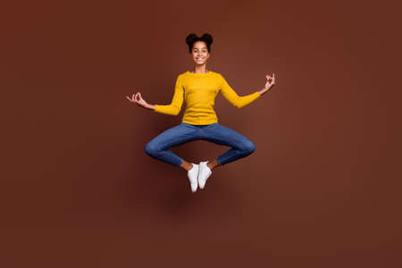 Full length photo of teen girl jump do asana wear shirt jeans sneakers isolated on brown color...