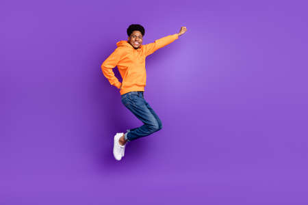 Full length photo of young brunet haired dark skin man jump up dream empty space fly isolated on purple color backgroundの写真素材