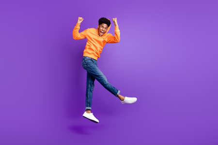 Full length photo of happy young afro american man jump up winner champion isolated on purple color backgroundの写真素材