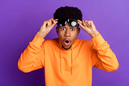 Photo of youong shocked dark skin man wear sunglass amazed sale news isolated on purple color...