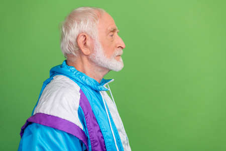 Photo of pretty serious senior man wear sportive suit looking empty space isolated green color backgroundの写真素材