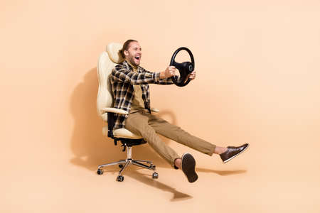 Full body profile side photo of young handsome man have fun driver isolated over beige color backgroundの写真素材