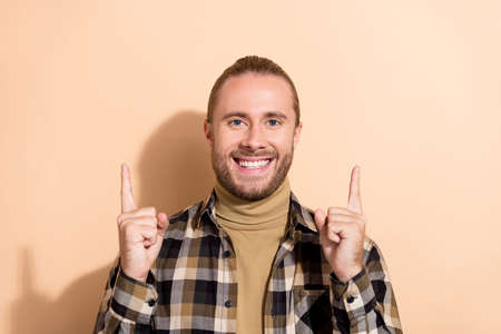 Photo of young man indicate fingers empty space promoter promo advertise isolated over beige color...