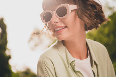 Photo of cute dreamy young lady dressed green shirt dark glasses walking smiling outdoors urban parkの写真素材