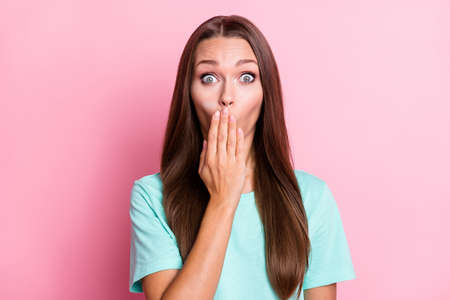 Photo portrait of amazed girl keeping secret closed mouth with hand isolated on pastel pink color...