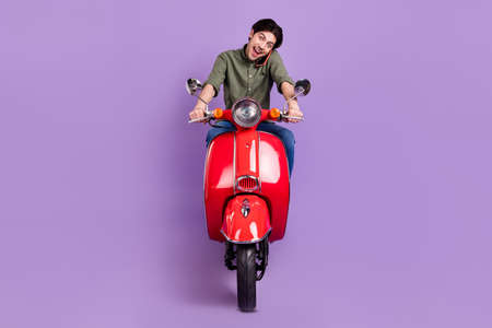 Full length photo of happy positive young man ride bike talk phone smile good mood isolated on...