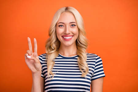 Portrait of attractive cheerful glad wavy-haired girl showing v-sign good mood isolated over bright...