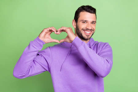 Photo of young man happy positive smile show fingers heart symbol love isolated over green color...