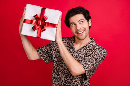 Portrait of young good looking smiling male look copyspace guess imagine new year gift isolated on...