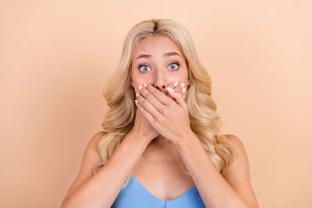 Photo of young woman close cover lips hands oops fail problem tell secret isolated over beige color backgroundの写真素材