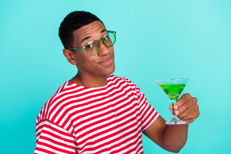 Photo of funky charming young man wear striped t-shirt smiling drinking cocktail isolated teal color backgroundの写真素材