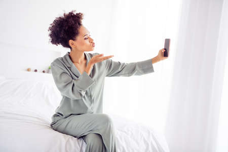 Photo of romantic affectionate lady take selfie portrait send bedtime kiss wear silky gown in light bedroom home indoorsの写真素材