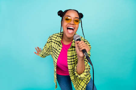 Photo of hipster trend buns hairdo sweet lady sing karaoke wear eyewear yellow shirt isolated on teal color backgroundの写真素材