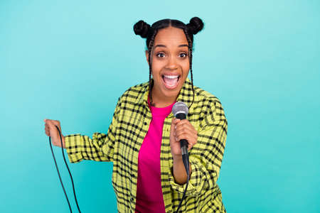 Photo of lovely trend buns hairdo cool famous lady sing in mic wear yellow shirt isolated on teal color backgroundの写真素材