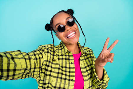 Photo of millennial trend top-knot hairdo lady do selfie show v-sign wear eyewear yellow shirt...