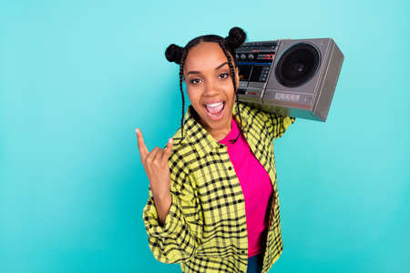 Photo of youth funky lady show rock sign hold boom box wear yellow shirt isolated on teal color backgroundの写真素材