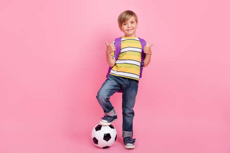 Full size photo of blonde little boy wear bag hands show thumb up game football isolated on pink...