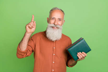 Photo of cheerful aged man hold book material learning idea choice isolated over green color...
