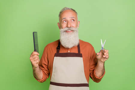 Photo of cheerful senior man haircut hair care wondered interested look empty space isolated over green color backgroundの写真素材