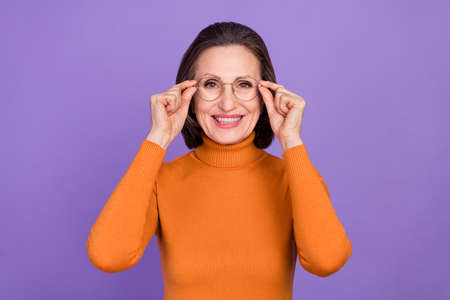 Photo of charming cute lady pensioner dressed orange turtleneck arms glasses smiling isolated purple...