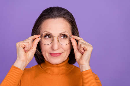 Photo of cute thoughtful lady pensioner dressed orange turtleneck arms glasses looking emty space...