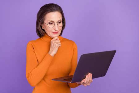 Photo of shiny intelligent lady pensioner dressed orange turtleneck glasses reading modern device...