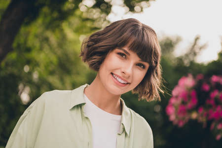 Portrait of attractive dreamy cheerful brown-haired girl spending sunny day at blooming garden fresh...