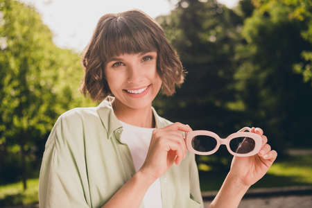 Photo portrait young girl with bob hair keeping sunglass smiling overjoyed walking on city streets