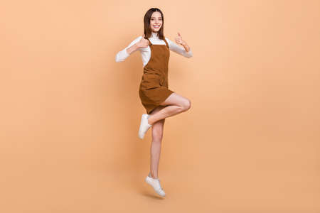 Full body photo of carefree cheerful pretty lady two hands show thumbs up isolated on beige color backgroundの写真素材